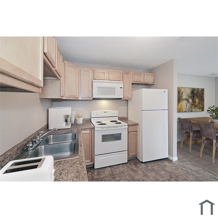 Renovated kitchen with white appliances, microwave above the stove, and maple cabinets